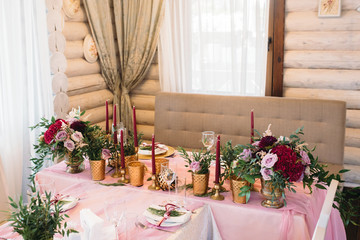 Tables for guests decorated in pink color with flowers, candles, gold vases and eucalyptus