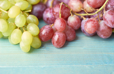 Green and pink grapes on a blue wooden background