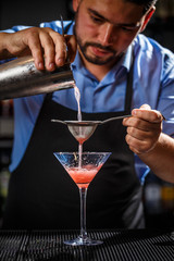 Expert barman is making cocktail