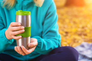 Woman with thermos of coffee in the autumn park