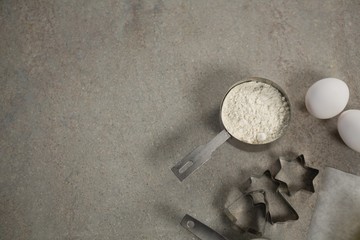 Overhead view of flour in measuring cup by moulds and egg