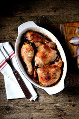 Baked chicken legs with red and white onions, with bacon and garlic.