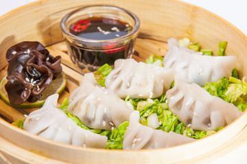 Close up various dim sum and sauce in bamboo steamer on the white background isolated. Chinese cuisine, selective focus