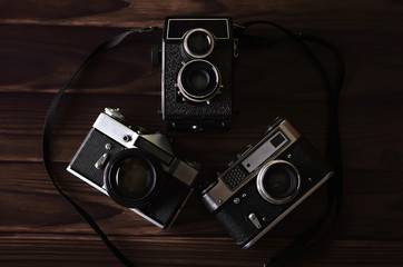 Three old vintage cameras on a wooden table.