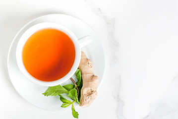 Cup of ginger tea with lemon,fresh mint and honey, on white marble table, copy space top view