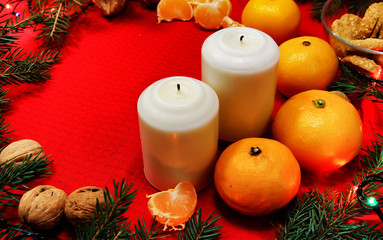 Christmas tree toys on a red napkin. Mandarins and candles on th