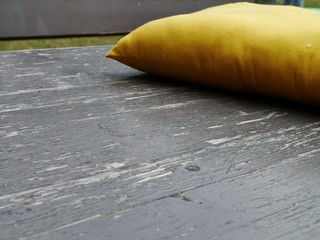 Gelbes Sofakissen auf einer Holzbank