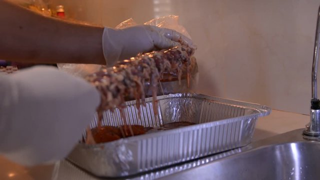men hands in white gloves prepering raw chicken hearts for bbq on kitchen