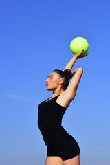 Woman gymnast in black sportswear with green ball.