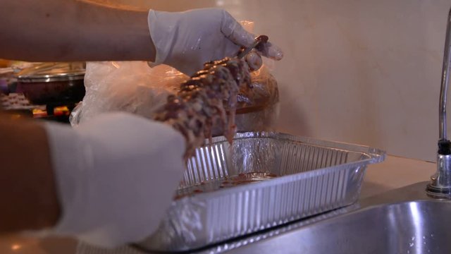 men hands in white gloves prepering raw chicken hearts for bbq on kitchen