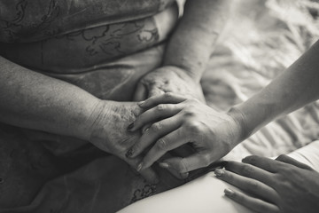 black and white people, age, family, care and support concept - close up of senior woman and young woman holding hands