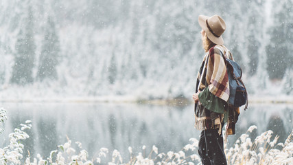 Beautiful traveling woman enjoying wilderness in front of stunning mountain lake. Winter is coming, first snowfall. Wanderlust and boho style © Alex from the Rock