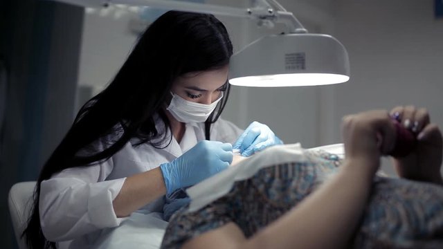 In the clinic, the cosmetologist does the client a mechanical facial cleansing