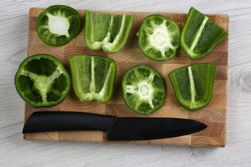 sliced sweet peppers with a ceramic knife on a wooden board
