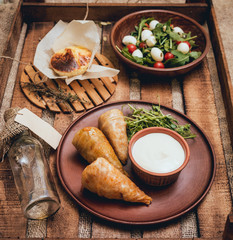 Tasty meat rolls with sour cream and salad on wooden table