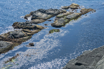 Landscape of rocky seashore with blue calm waters in sunny summer day as natural background