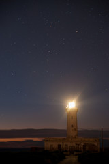 Lighthouse in the night against a starry sky