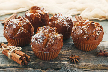 Tasty muffins with cinnamon and star anise on wooden table