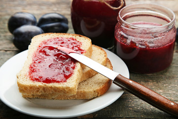 Bread with plum jam on grey wooden table