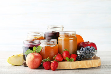 Glass jars with different kinds of jam on wooden table