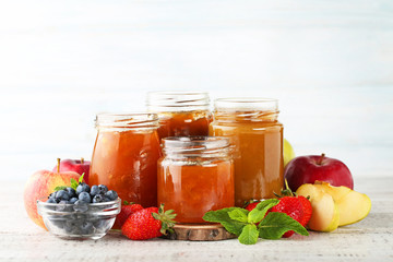 Glass jars with different kinds of jam on wooden table
