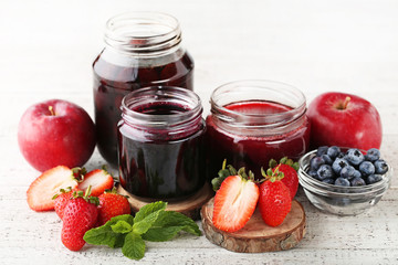 Glass jars with different kinds of jam on wooden table