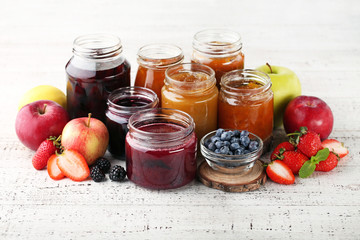 Glass jars with different kinds of jam on wooden table
