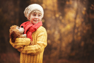 Little girl holding a lot of soft toys dog in the hands. Girl on a background autumn forest and grass.