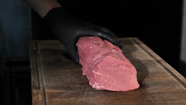 chef chefs cut a piece of meat in black gloves