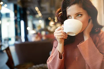 Tuinposter woman drinking coffee in a cafe © Izabela Magier
