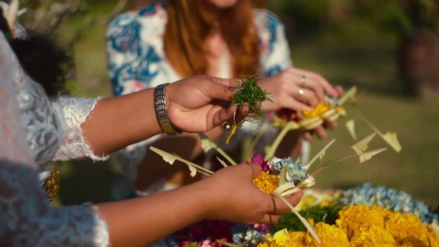 Close up of women hands making canang sari balinese offerings. Shot with Sony a7s and Atomos Ninja Flame on sunny summer day in Bali, Indonesia.