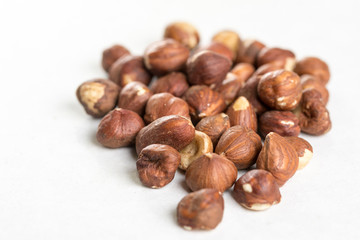 Pile of raw hazelnuts isolated above white marble stone