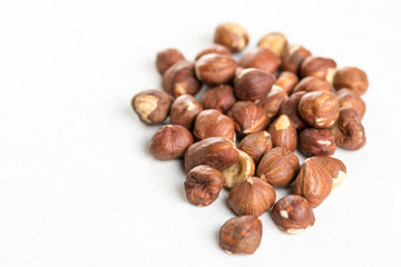 Pile of raw hazelnuts isolated above white marble stone