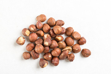 Pile of raw hazelnuts isolated above white marble stone