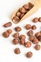 Raw hazelnuts on the white background with wooden spatula spoon