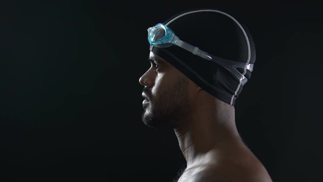 Professional male swimmer preparing for relay, looking at pool, close up of face