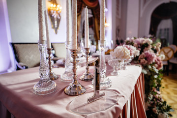 Plates with bread stand among sparkling glassware on table served for wedding dinner