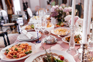 Plates with bread stand among sparkling glassware on table served for wedding dinner