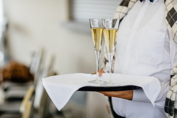 Waitress holding a dish of champagne and wine glasses at some festive event, party or wedding reception