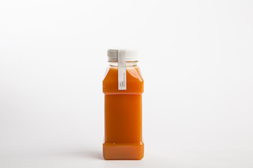 Pressed organic orange juice in plastic bottle on the white background. Nutrition detox juice. Healthy carrot fresh juice. Small size bottle