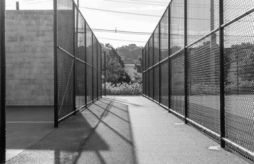 Gated tennis and handball court area. Chainlink fence sport active area. Racket ball sports area. Park and recreation field.