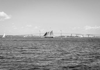 Isolated large sailing sail boat. Large ship in ocean. Roaring waves. Bridge background. Abstract color background.