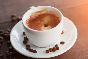 Hot Coffee cup with Coffee beans on the wooden table on morning sunshine