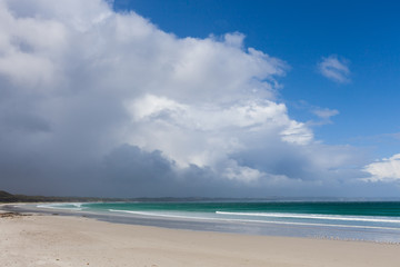 White sand beautiful ocean beach under stormy clouds and blue sky