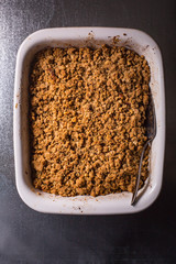 Apple crumble - traditional fall dessert in a baking dish. Dark background 