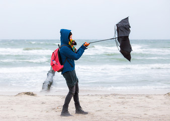 a woman tries to hold an umbrella in a storm
