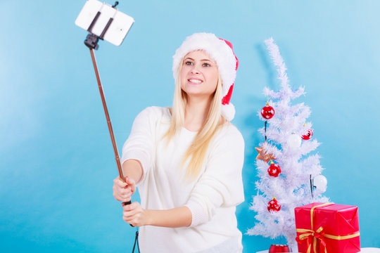 Girl in santa hat taking picture of herself using selfie stick