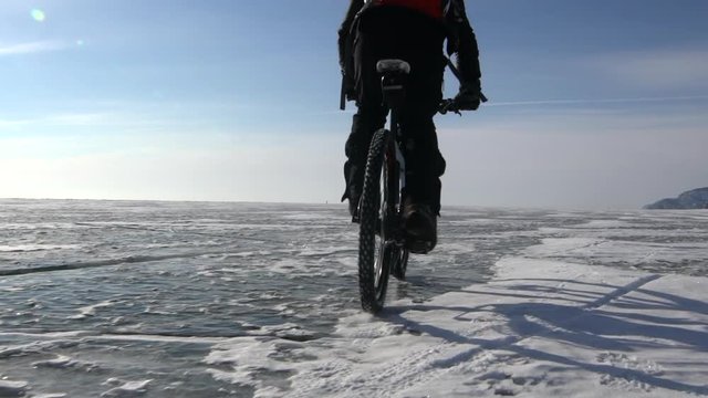 a man riding a bicycle across a frozen lake