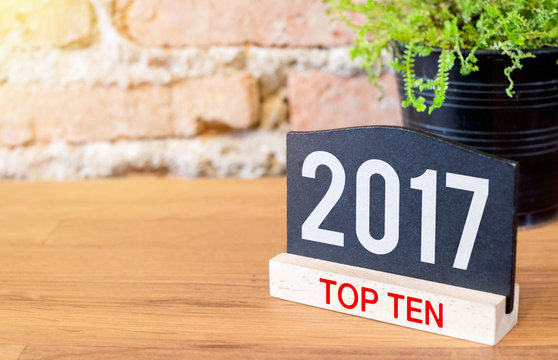 New year 2017 top ten topic number on blackboard sign and green plant on wood table at brick wall
