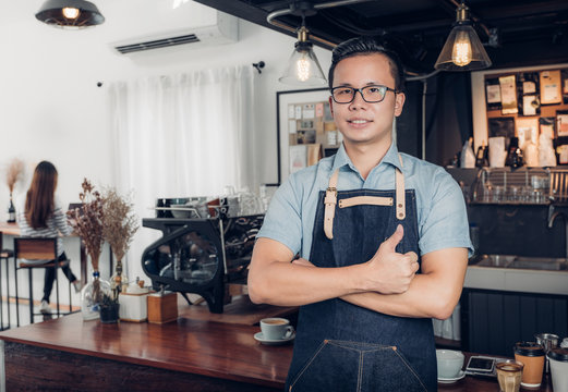 Male Barista thumbs up in front on cafe counter bar with customer sitting inside coffee shop,Good owner food and drink business,success shop